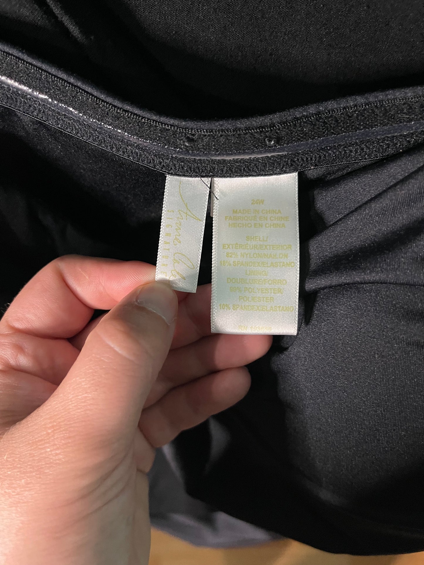 Person holding a label on a black garment with text